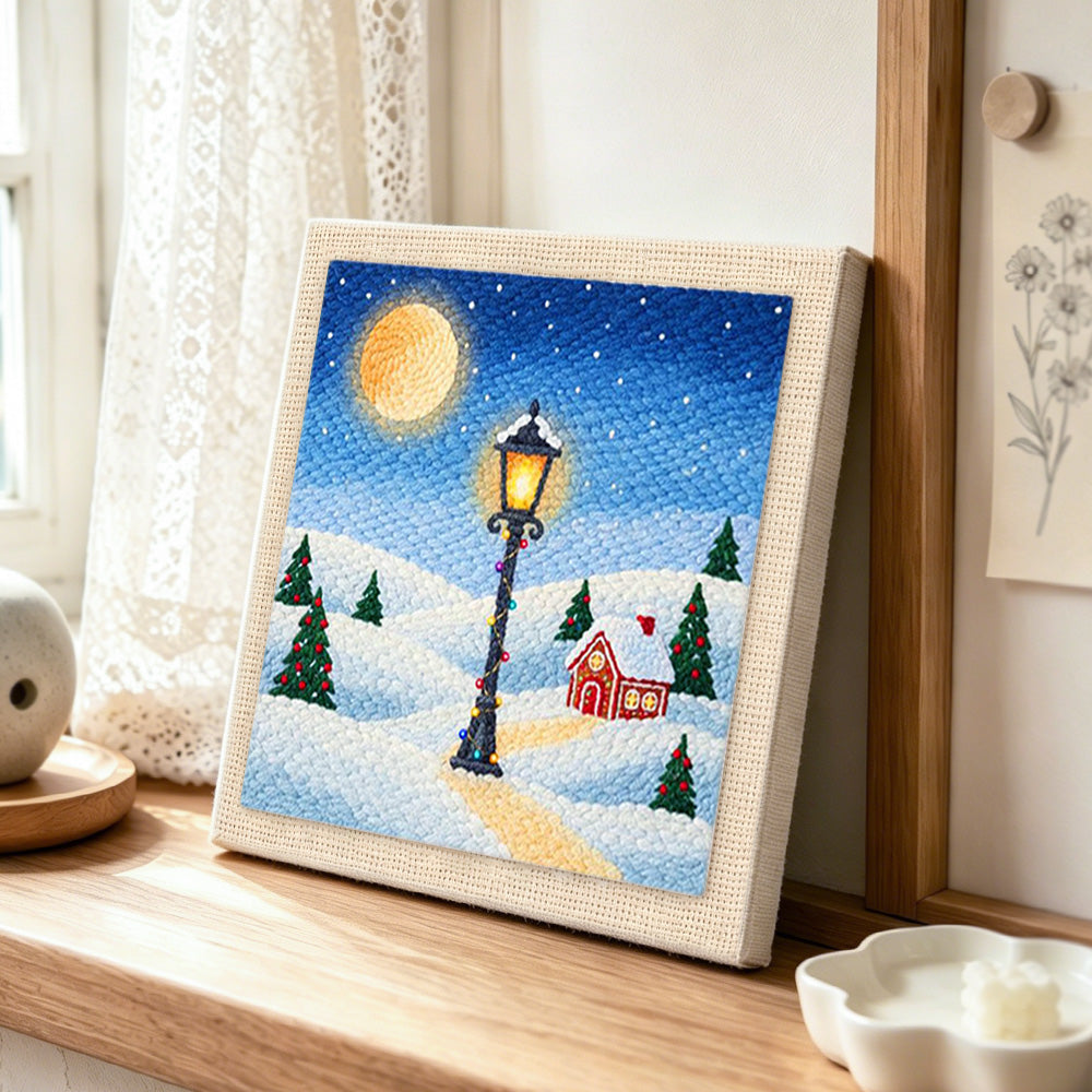 Snowy street lamp scene punch needle artwork displayed on a table