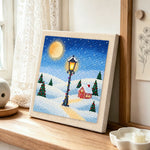 Snowy street lamp scene punch needle artwork displayed on a table