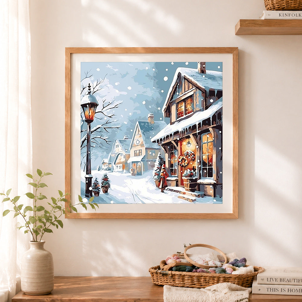 Finished snowy winter village street cross stitch artwork displayed as home decor