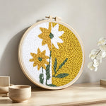 Split-tone dandelion flower punch needle artwork displayed on a table