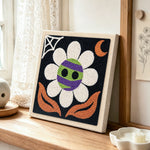 Spooky striped flower punch needle artwork displayed on a table