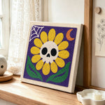 Spooky sunflower with skull punch needle artwork displayed on a table