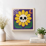 Finished spooky sunflower with skull artwork displayed on a wall