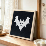 Spooky white bat punch needle artwork displayed on a table