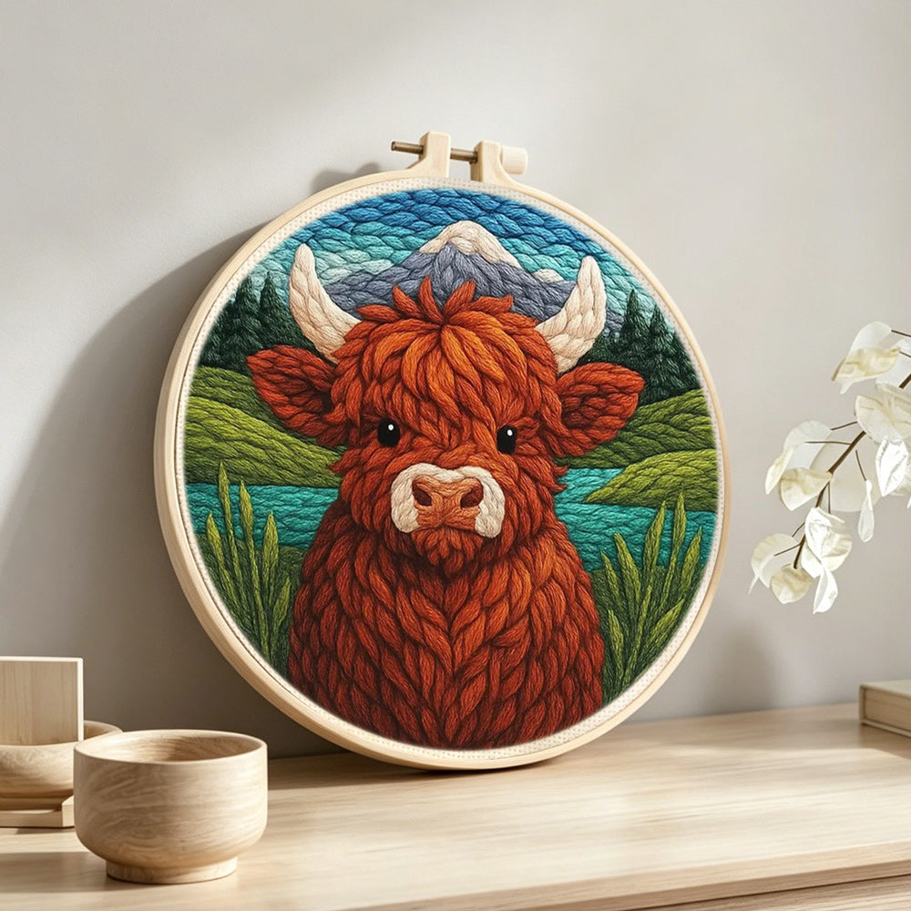 Springtime highland cow and mountain lake punch needle artwork displayed on a table