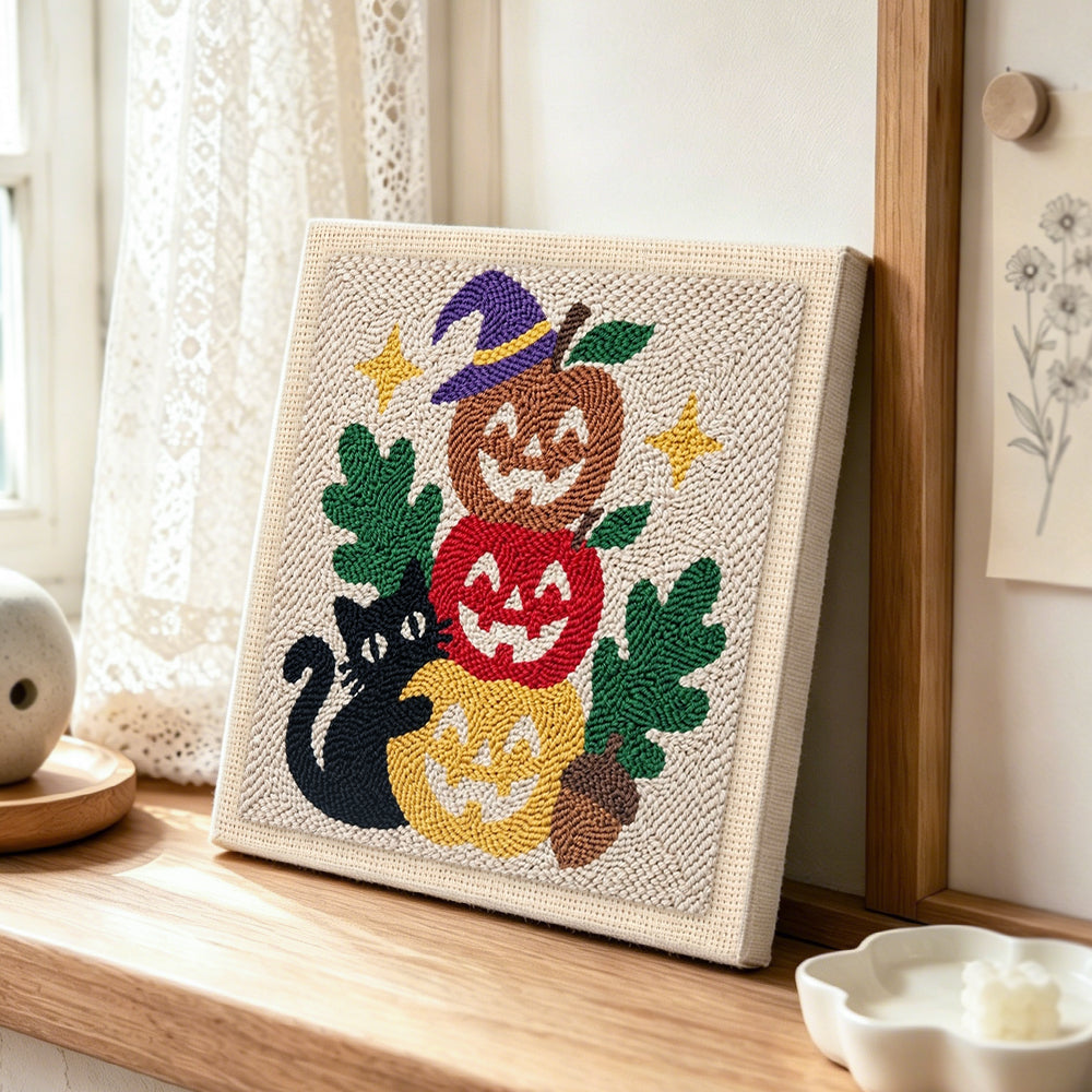 Stacked pumpkins with black cat punch needle artwork displayed on a table