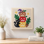 Finished stacked pumpkins with black cat artwork displayed on a wall