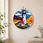 Starry night lighthouse and cottage needle felt wall art displayed in a bright home interior