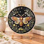 Starry night moth embroidery kit finished hoop displayed on a wooden stand as cozy tabletop decor