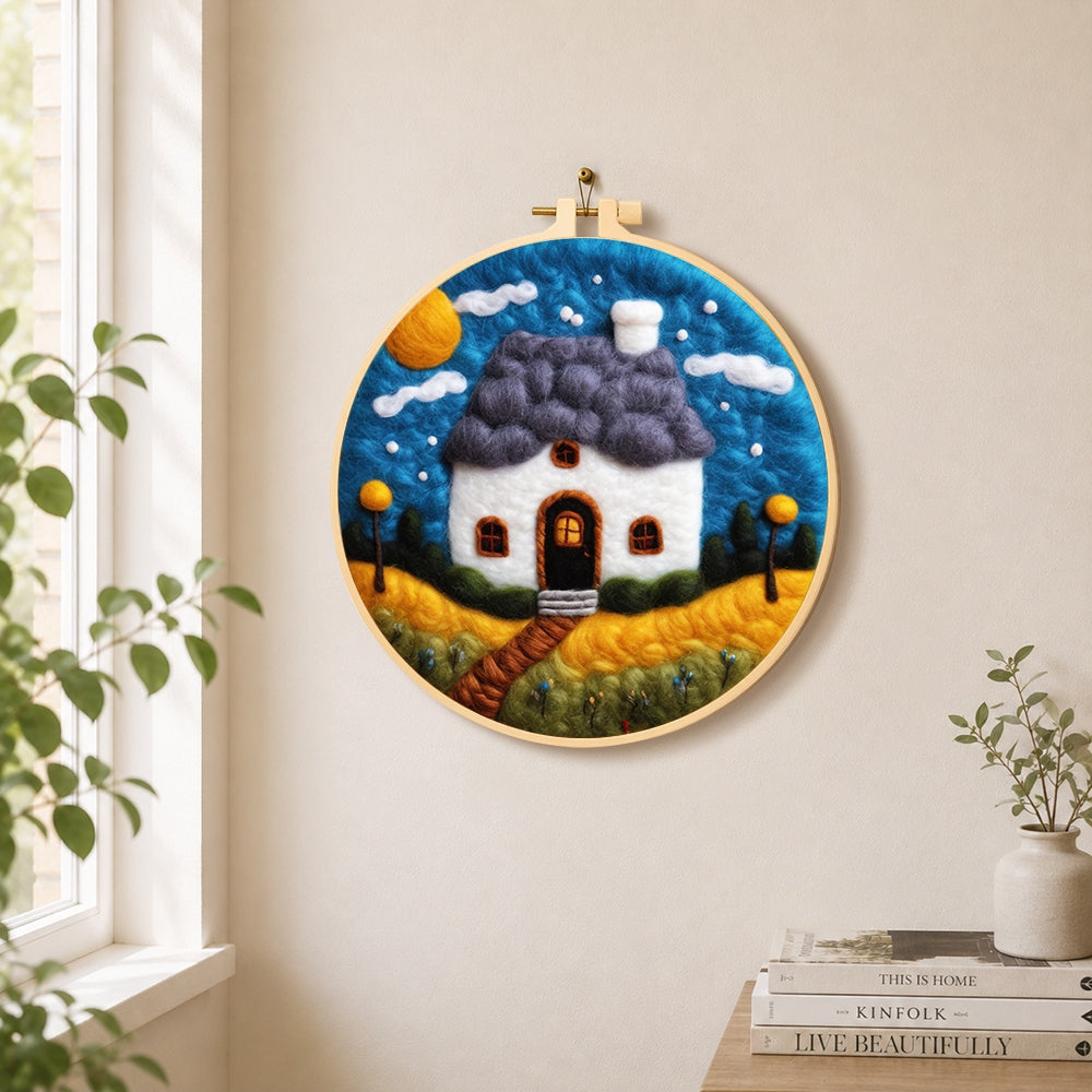 starry sky and blue roof cottage needle felt wall art displayed in a bright home interior