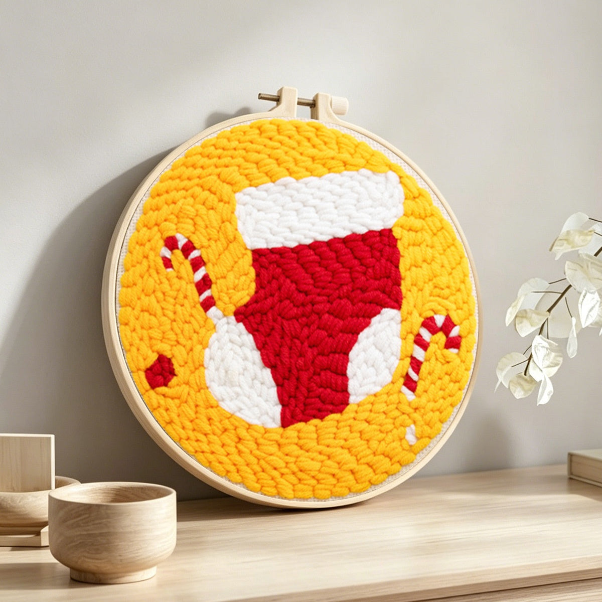 Stocking and candy canes punch needle artwork displayed on a table