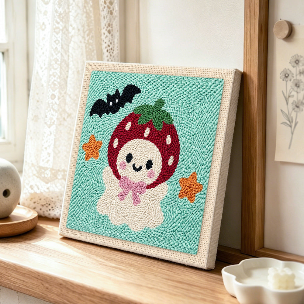Strawberry ghost punch needle artwork displayed on a table