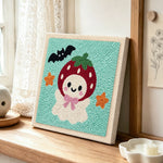 Strawberry ghost punch needle artwork displayed on a table