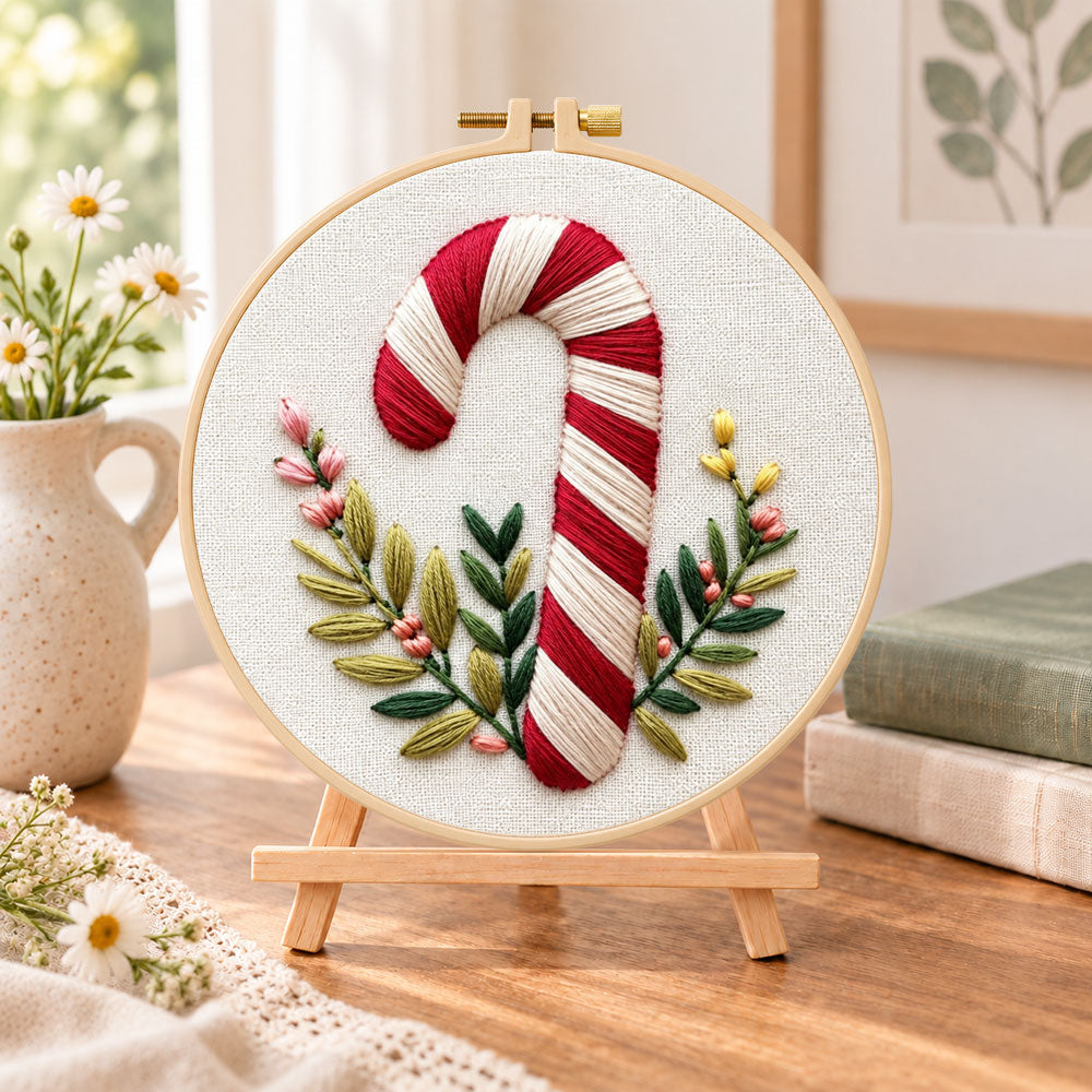 Striped candy cane embroidery kit finished hoop displayed on a wooden stand as cozy tabletop decor
