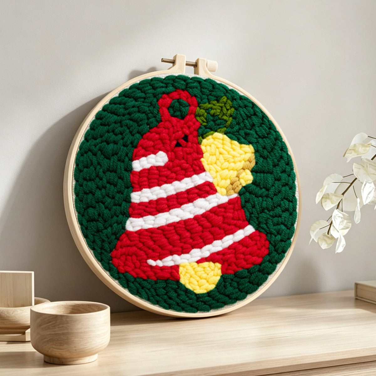 Striped christmas bell punch needle artwork displayed on a table