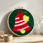 Striped christmas bell punch needle artwork displayed on a table