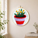 Striped pot with yellow flowers needle felt wall art displayed in a bright home interior