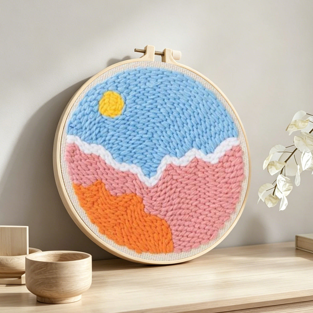 Sun over colorful clouds punch needle artwork displayed on a table