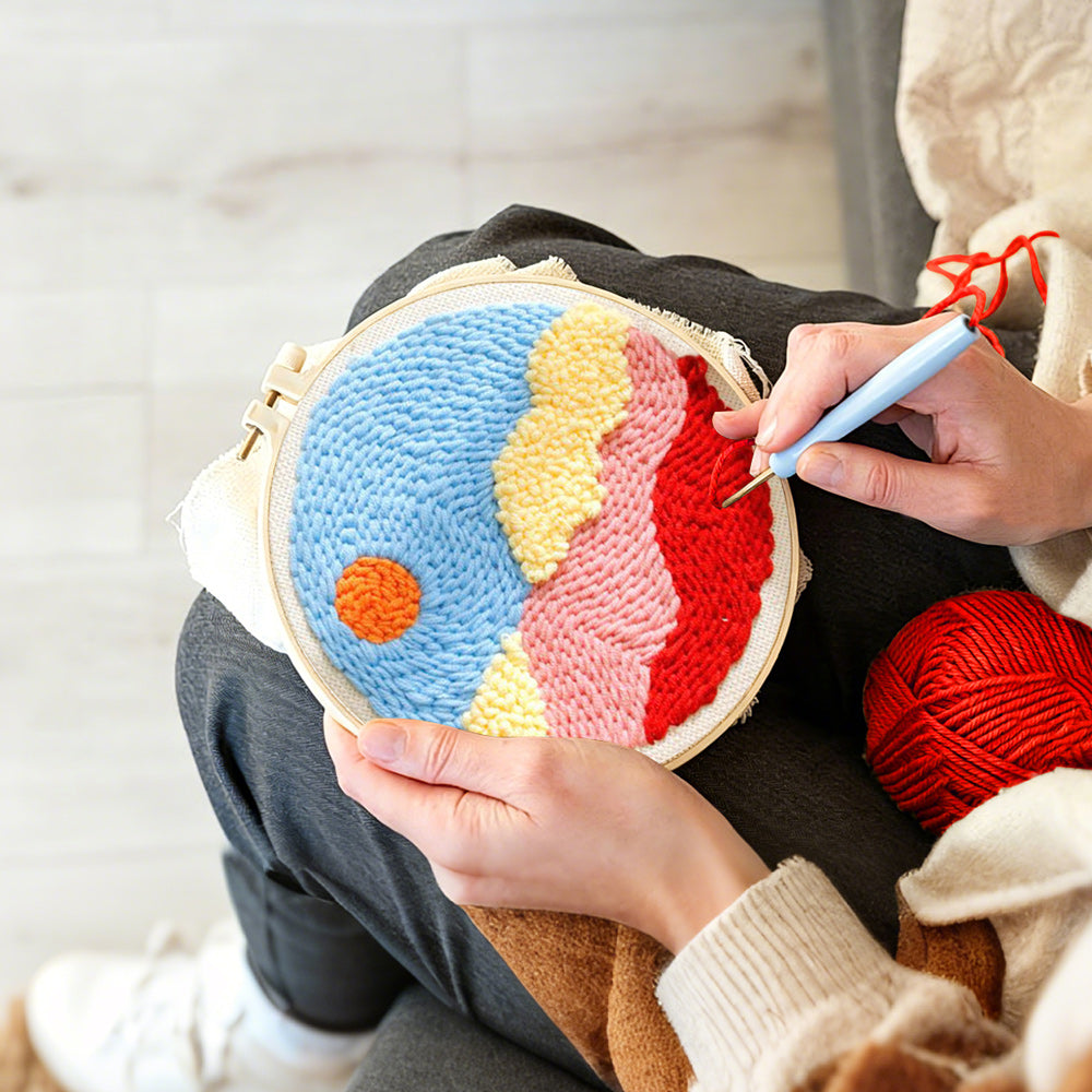 Creating handmade sun over colorful mountains and clouds punch needle artwork
