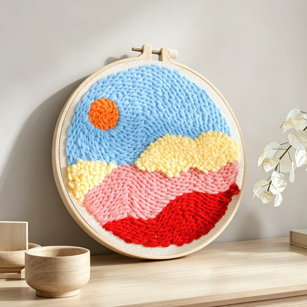 Sun over colorful mountains and clouds punch needle artwork displayed on a table
