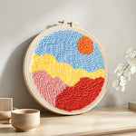Sun over colorful mountains punch needle artwork displayed on a table