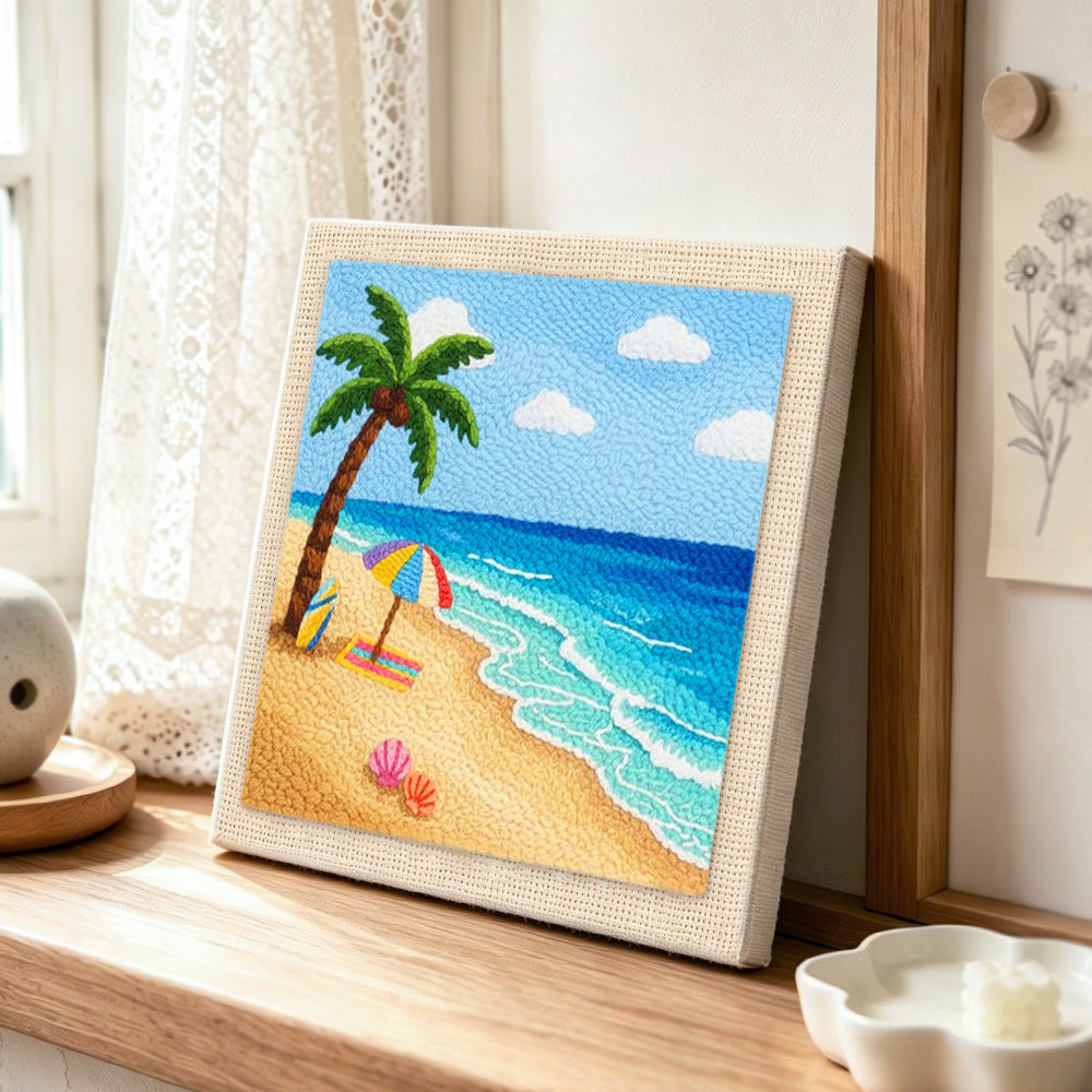 Sunny beach, umbrella and surfboard punch needle artwork displayed on a table