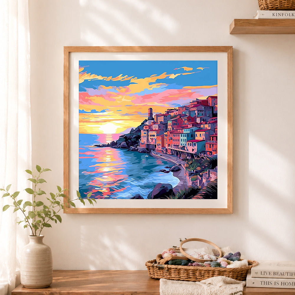 Finished sunset cliffside coastal village cross stitch artwork displayed as home decor