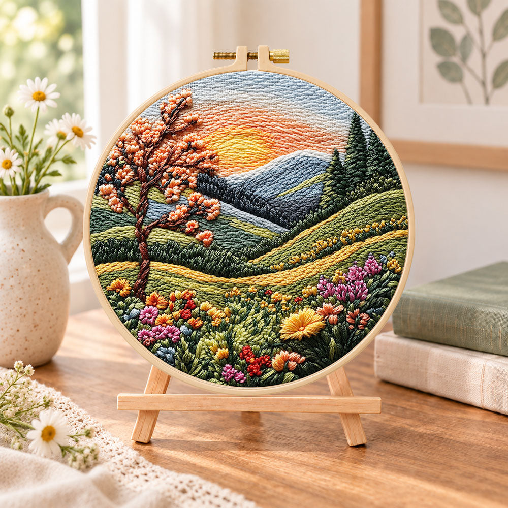 Sunset mountain bloom embroidery kit finished hoop displayed on a wooden stand as cozy tabletop decor