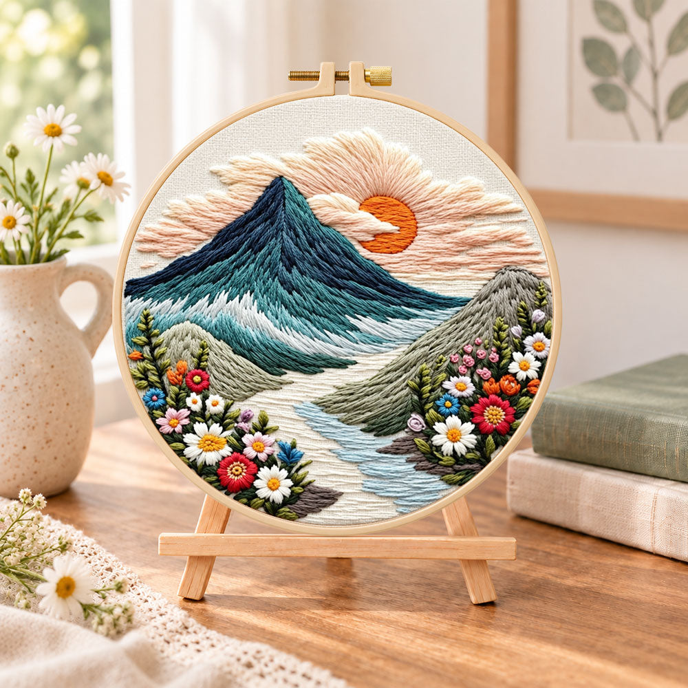 Sunset over mountain peaks embroidery kit finished hoop displayed on a wooden stand as cozy tabletop decor