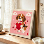 Sweet beagle puppy holding a big heart punch needle artwork displayed on a table