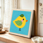 Sweet little yellow bird with green wing punch needle artwork displayed on a table