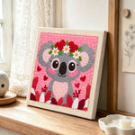 Sweet pink koala with heart flower crown punch needle artwork displayed on a table