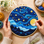 Creating the swirling night sky with stars and blue clouds wool painting by hand with a felting needle