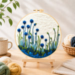 Finished tall blue wildflowers on white needle felting displayed on a wooden easel