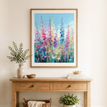 Finished tall colorful foxglove flowers on blue cross stitch artwork displayed as home decor