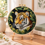 Tiger among green leaves embroidery kit finished hoop displayed on a wooden stand as cozy tabletop decor
