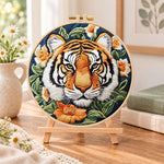 Tiger surrounded by blooms embroidery kit finished hoop displayed on a wooden stand as cozy tabletop decor