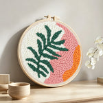 Tropical leaf and sunset tones punch needle artwork displayed on a table