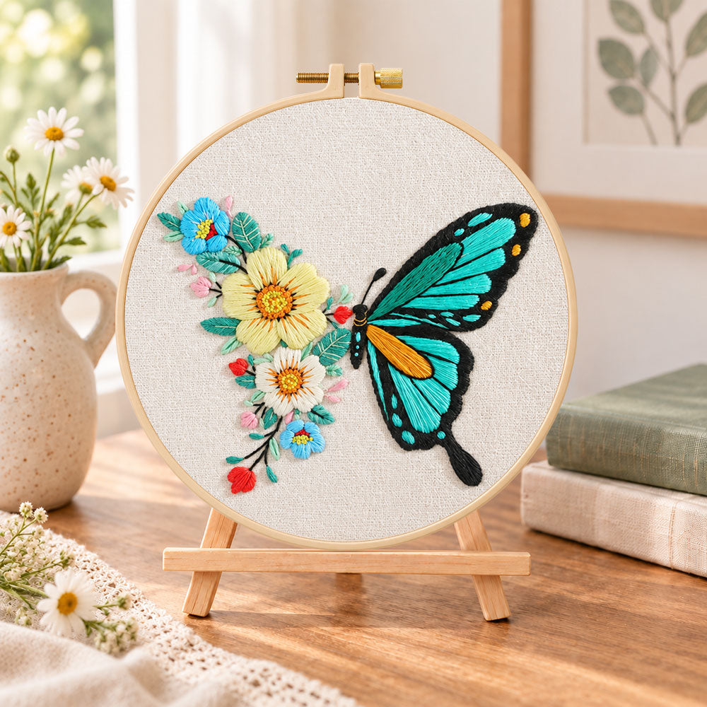 Turquoise butterfly and blooms embroidery kit finished hoop displayed on a wooden stand as cozy tabletop decor