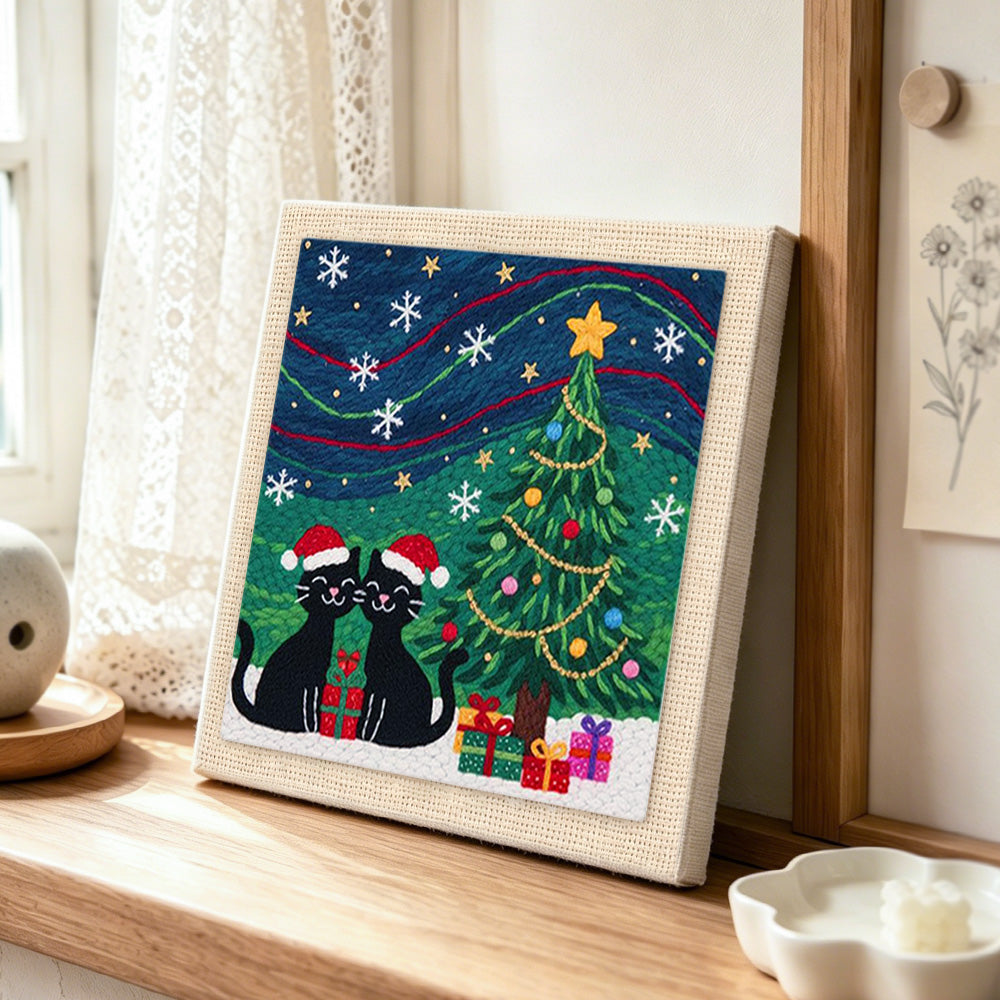 Two black cats under christmas tree punch needle artwork displayed on a table