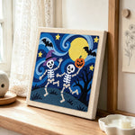 Two skeletons dancing at night punch needle artwork displayed on a table