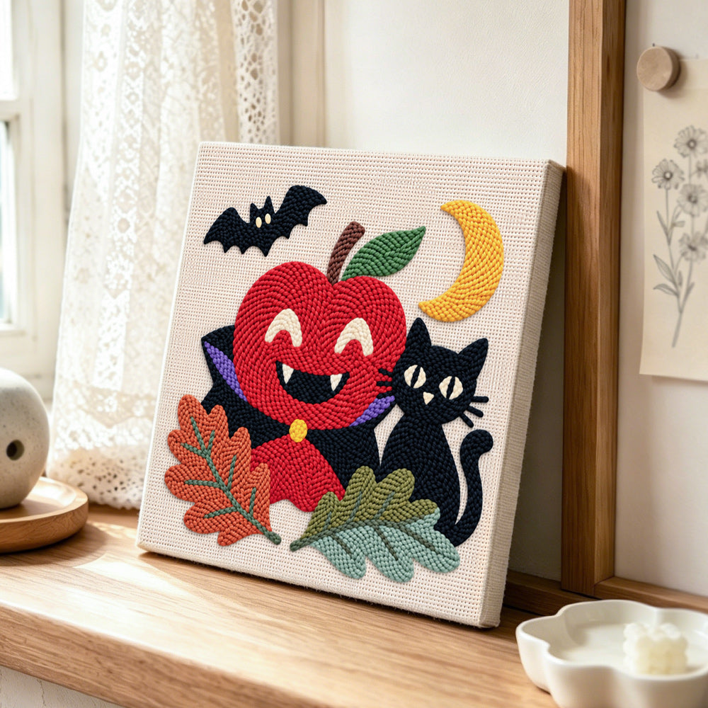 Vampire apple and black cat punch needle artwork displayed on a table