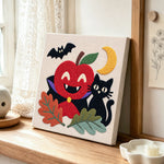 Vampire apple and black cat punch needle artwork displayed on a table