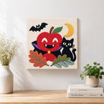 Finished vampire apple and black cat artwork displayed on a wall