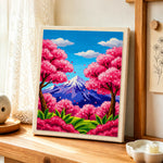 Vibrant cherry blossom trees and snowy peak punch needle artwork displayed on a table