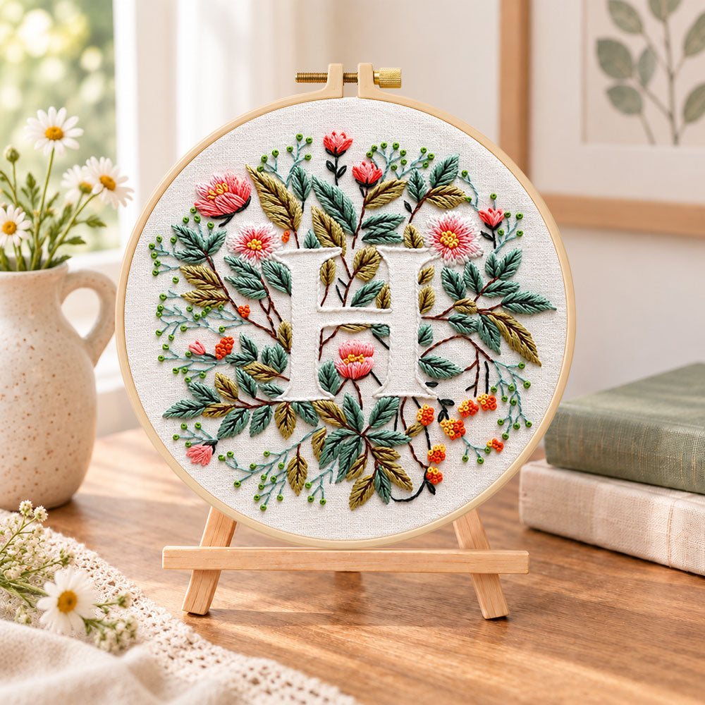 Vintage leaf blooms and letter h embroidery kit finished hoop displayed on a wooden stand as cozy tabletop decor