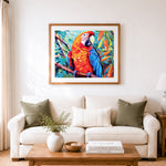Finished vivid red and blue macaw cross stitch artwork displayed as home decor