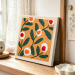Warm apricot floral punch needle artwork displayed on a table