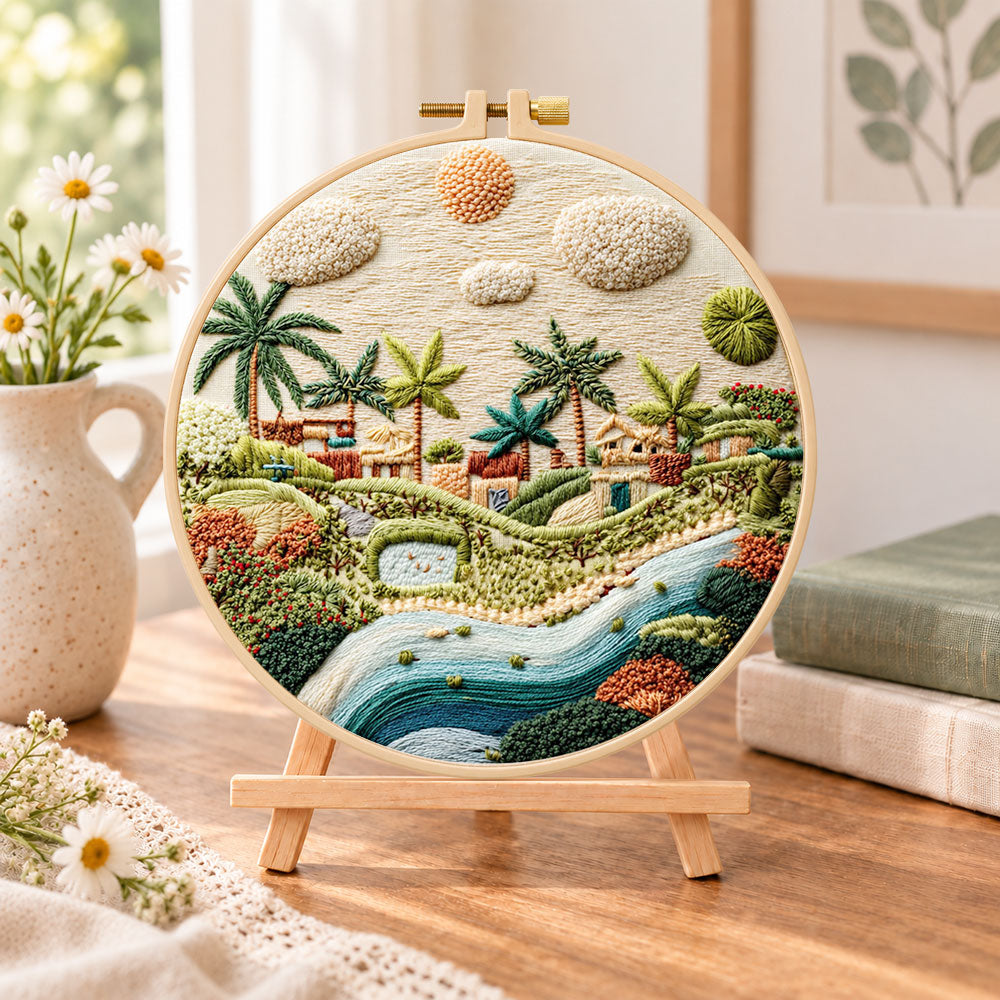 Warm sunlit village embroidery kit finished hoop displayed on a wooden stand as cozy tabletop decor