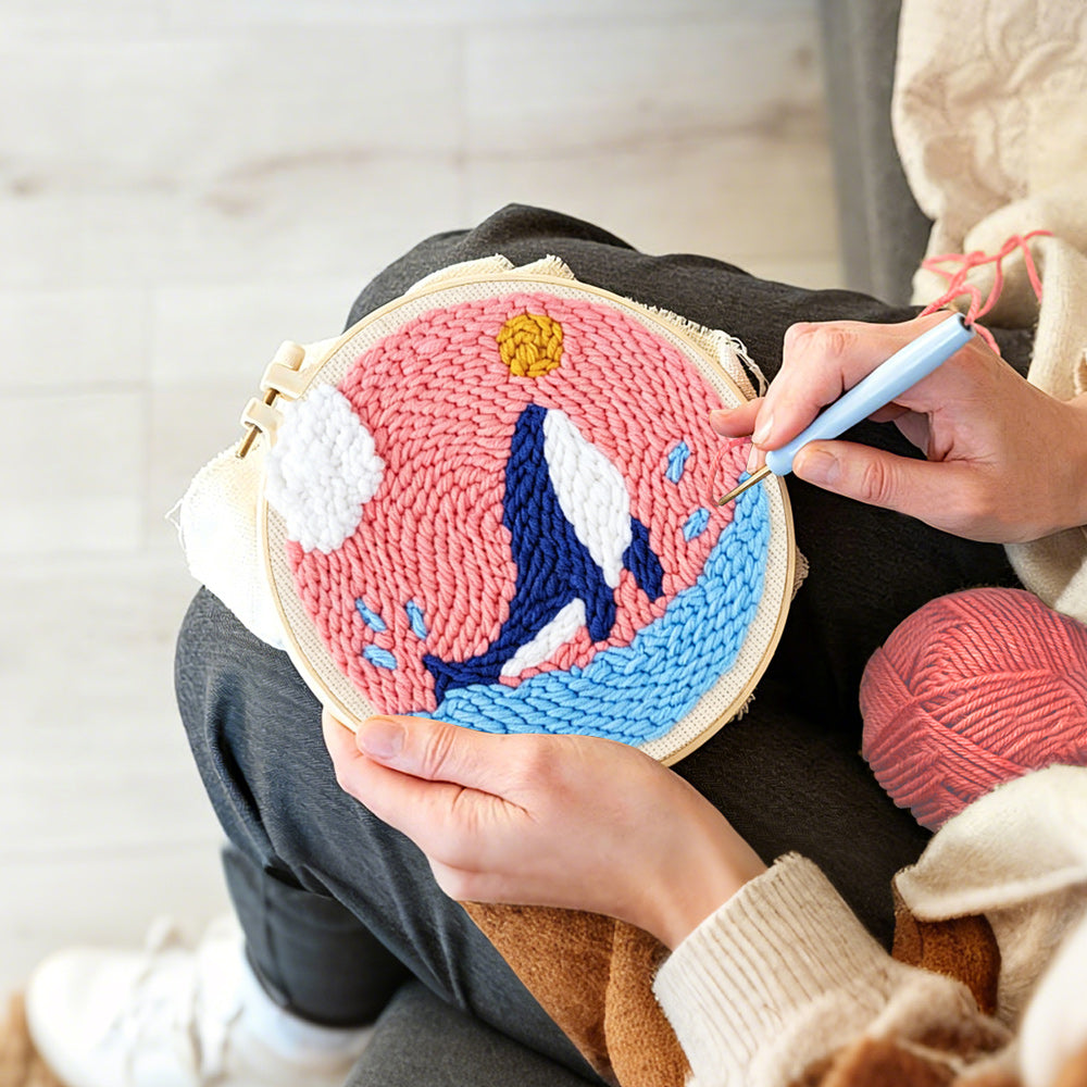 Creating handmade whale jumping in pink sky punch needle artwork